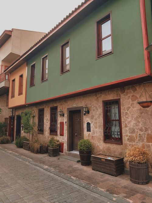 Free A picturesque street lined with rustic two-story houses and lush potted plants, offering an old-world charm. Stock Photo