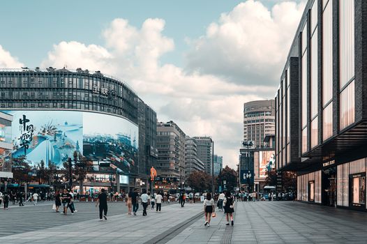 Lively urban plaza scene with modern architecture and people walking.