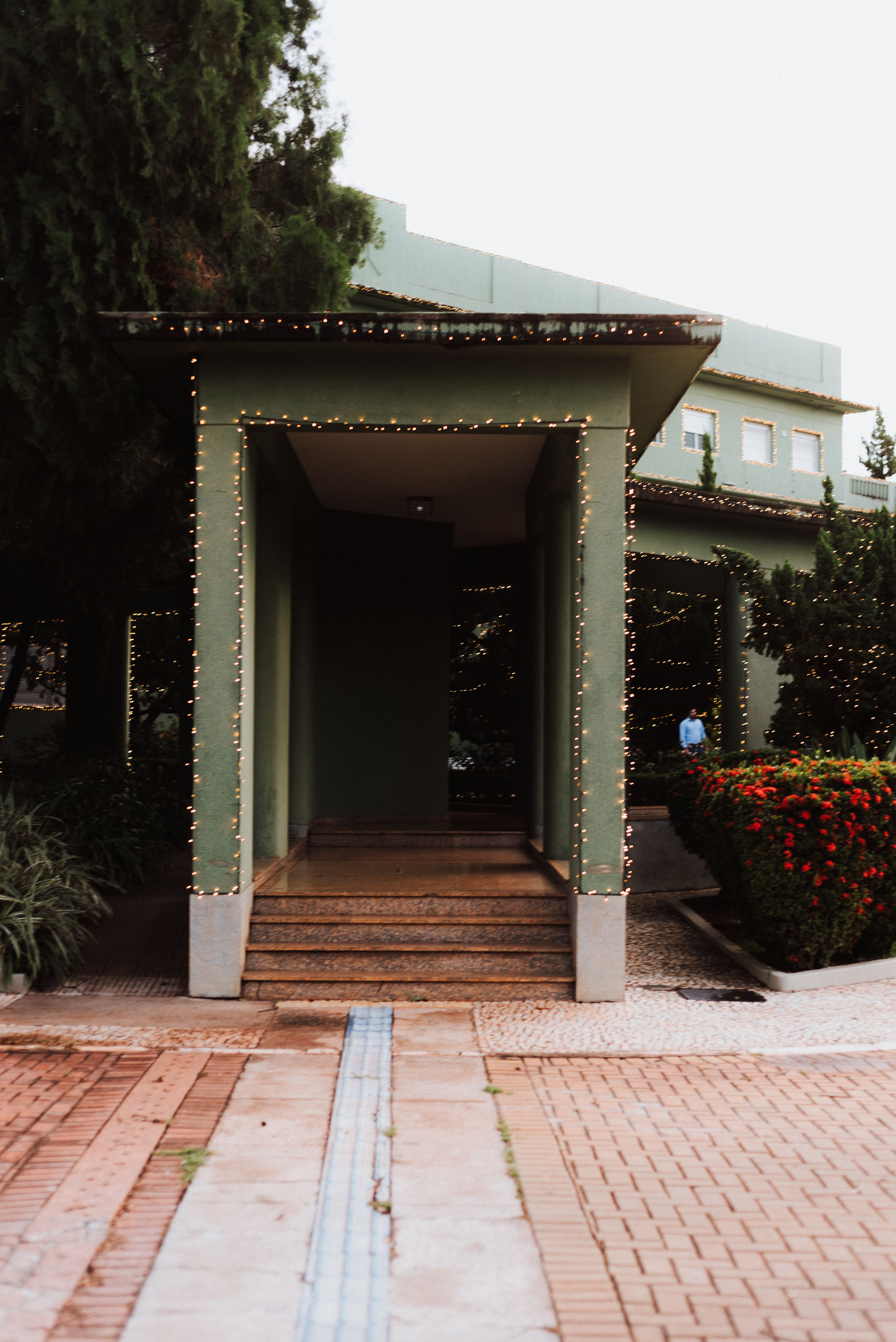 Elegant entrance of a green house in Goiânia, Brazil, adorned with festive lights and lush greenery.