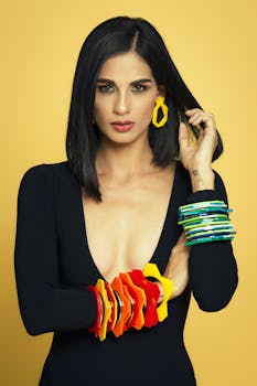 在黄色背景下，时尚女性戴着彩色手镯和耳环摆姿势