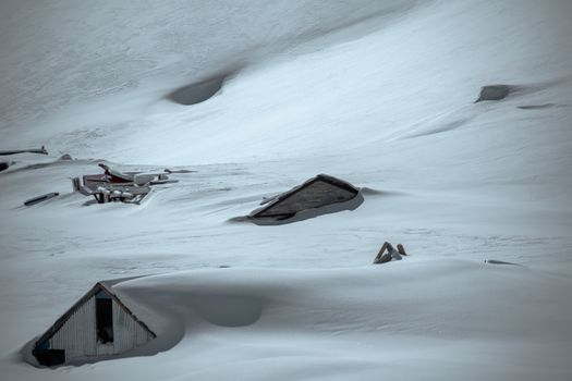 Abandoned houses buried under snow, showcasing winter's harsh impact.