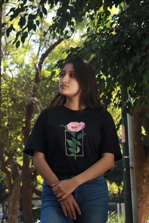 Free Brunette woman in a park wearing a black T-shirt with floral design posing thoughtfully. Stock Photo