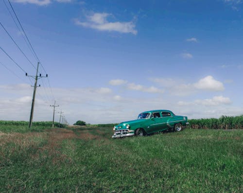 Green Vintage Car on Grass Field Under Blue Sky