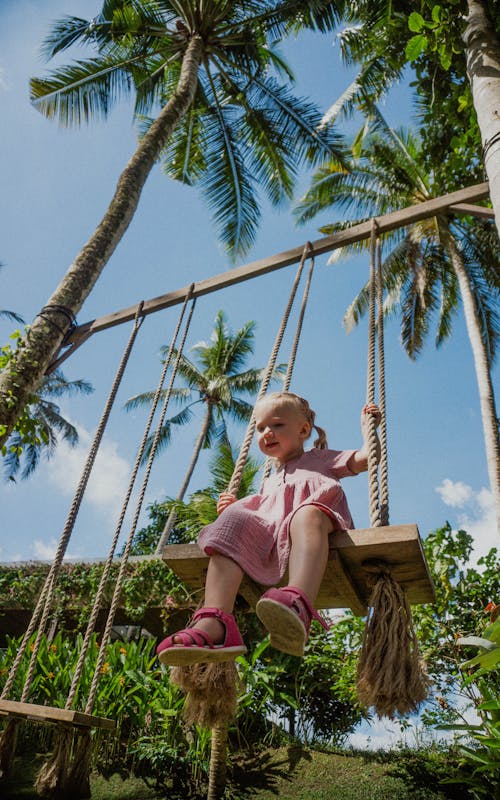 Girl Sitting on Swing in Tropical Landscape