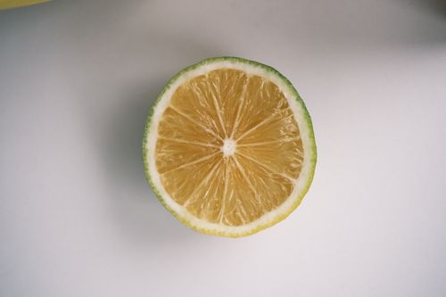 Free Close-up of a fresh lime slice on a smooth white surface, showcasing its juicy texture. Stock Photo