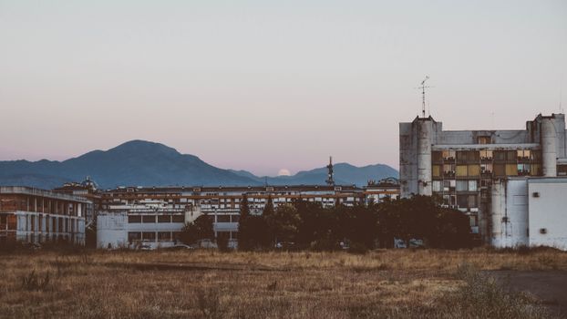 An urban scene with industrial buildings and distant mountains under a twilight sky.