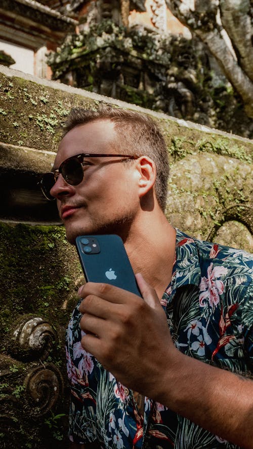 A Man in Aloha Shirt Holding a Black iPhone