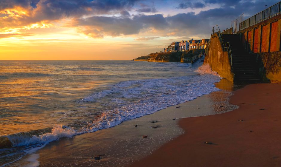 Vibrant sunset over a picturesque coastal town and sandy beach.