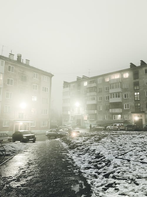 Cars Parked Near Concrete Buildings during Foggy Weather