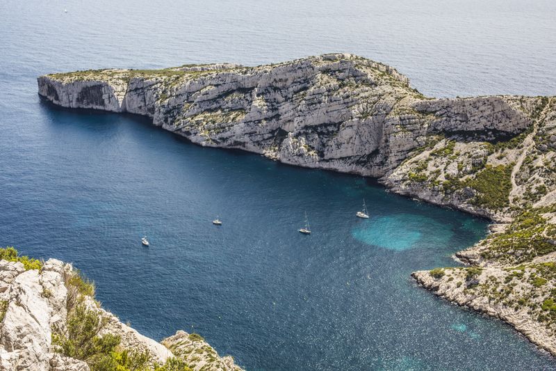 Sailboats gliding across a deep blue bay surrounded by coastal scenery