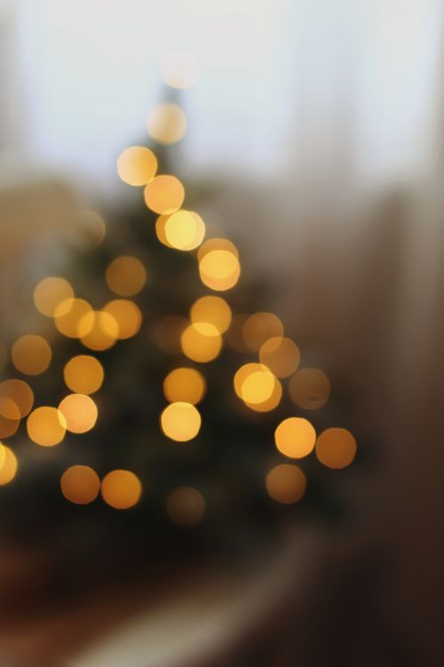 Free A beautifully blurred view of a Christmas tree with warm bokeh lights indoors, creating a cozy holiday atmosphere. Stock Photo