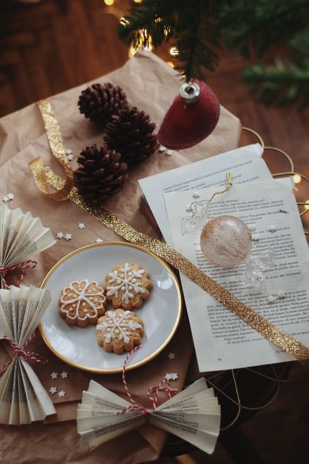 Cookies decorated with icing alongside Christmas ornaments and pinecones.