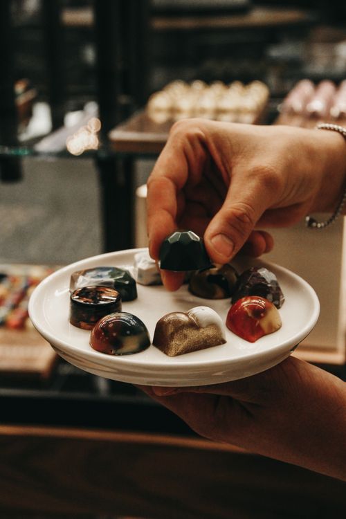 Free Assorted gourmet chocolates are elegantly presented with a hand showcasing their intricate designs. Stock Photo