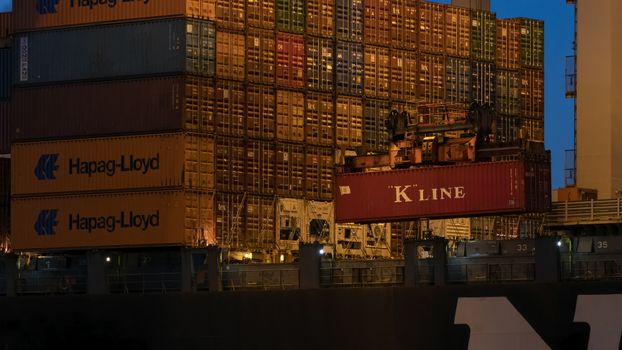 Close-up of stacked shipping containers at Rotterdam port during twilight.