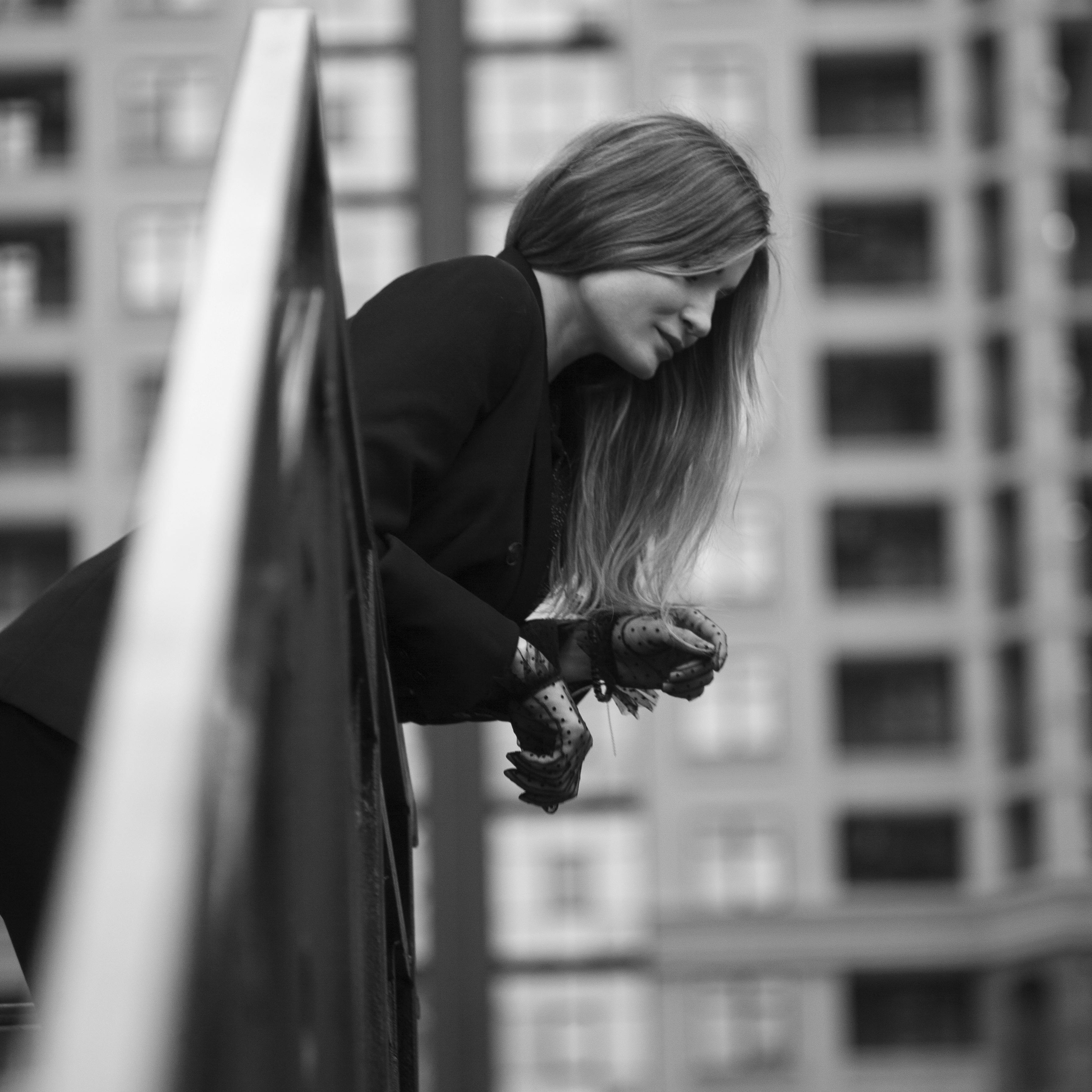 Woman with Long Hair Wearing Gloves Leaning on Metal Railing