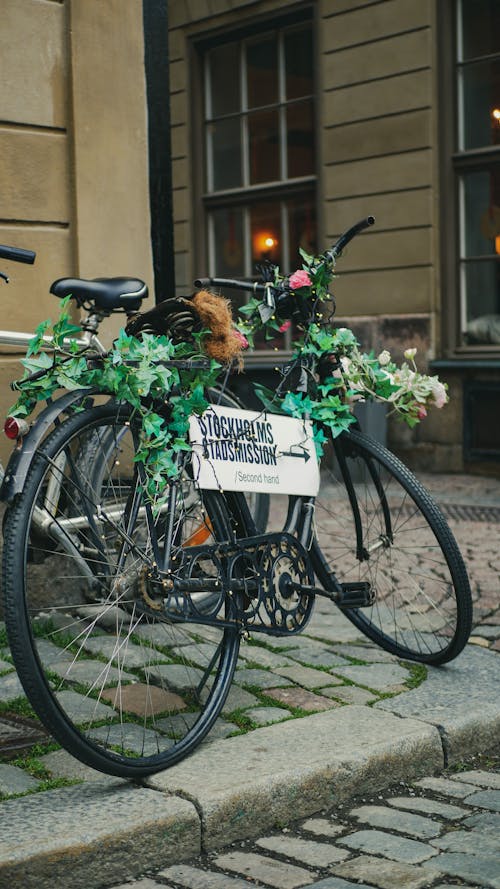 A Black Bicycle Decorated with Aesthetic Leaves and Signage Parked on Sidewalk