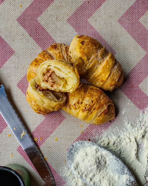 Free Appetizing croissants with scattered flour, shot from above on a patterned tablecloth. Stock Photo