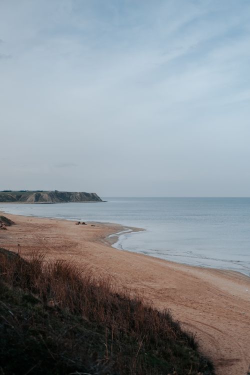 Free A tranquil beach scene at dusk with calm sea and sandy shoreline. Ideal for nature-inspired designs. Stock Photo