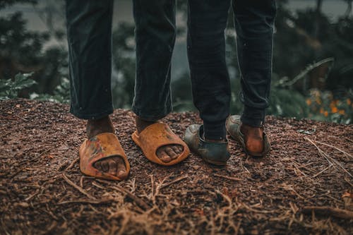 Feet of Two Boys Wearing Dirty Footwear in Bad Condition