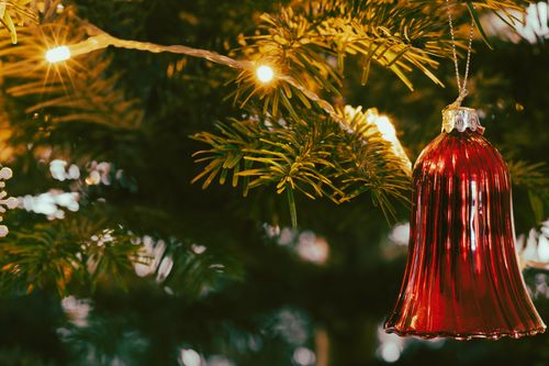 Free Close-up of a red glass bell ornament on a Christmas tree, illuminated by warm lights. Stock Photo