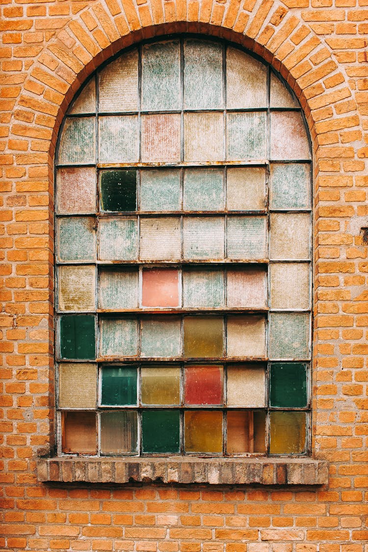 Dirty Panes Of An Arched Window In A Brick Wall