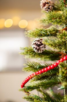 Close-up of a decorated Christmas tree with red beads and snow-dusted pine cones.