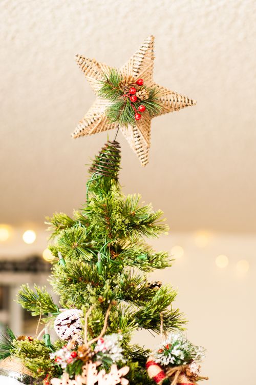 Free Close-up of a Christmas tree topper featuring a woven star ornament with pine needles and berries. Stock Photo
