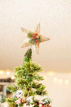 A beautifully decorated Christmas tree indoors with a woven star topper, depicting holiday cheer.