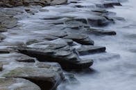 苔藓覆盖的岩石上层叠着宁静的水景，营造出朦胧而宁静的景象