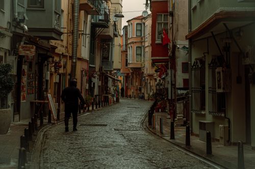 Free A person walks down a historic cobblestone street in Fatih, Istanbul, lined with colorful buildings. Stock Photo