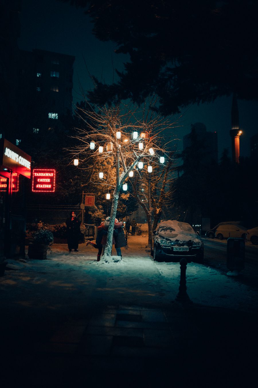 Karlı bir gecede ışıklarla süslü bir ağaç
