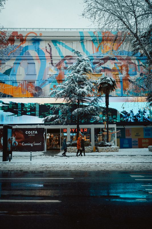 Renkli bir duvar resmi ve yayalarla karlı bir sokak