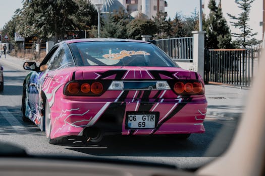 A vibrant pink sports car with striking livery driving through urban streets in Turkey.