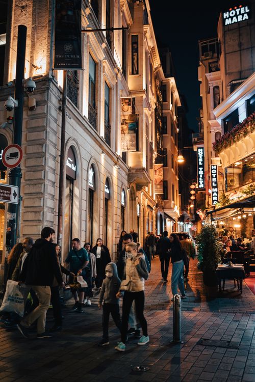 Free A lively city street bustling with people and illuminated by vibrant lights at night. Stock Photo