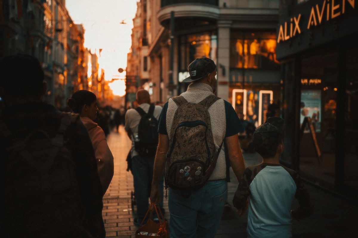 Gün batımında hareketli bir caddede yürüyen baba ve oğul