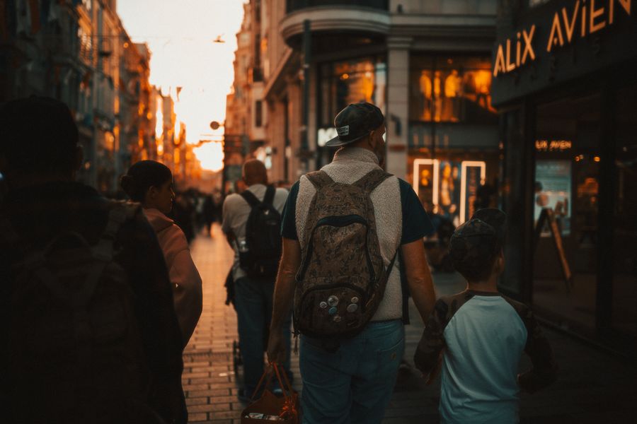 Gün batımında hareketli bir caddede yürüyen baba ve oğul