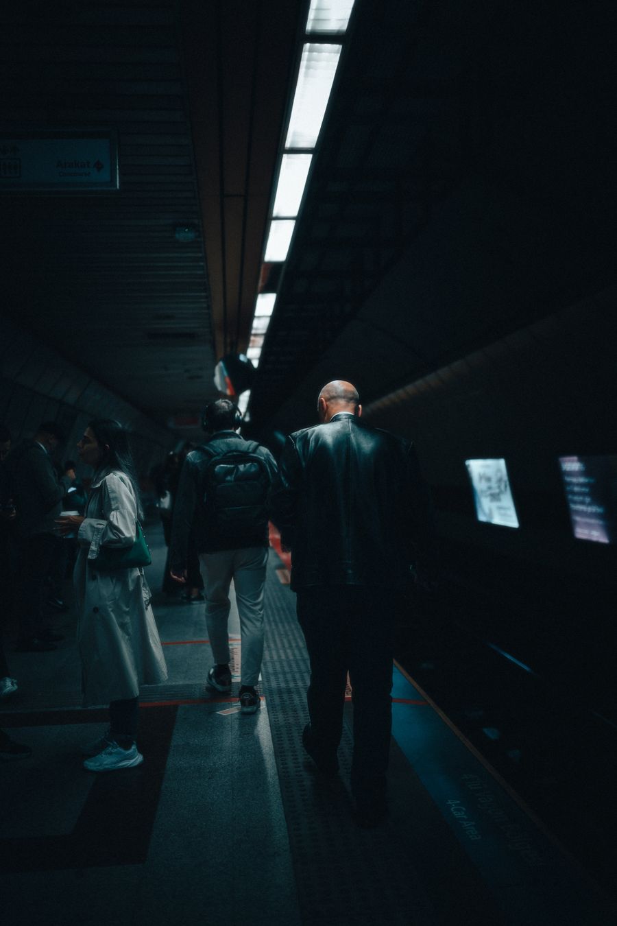 Loş bir metro peronunda yolcular