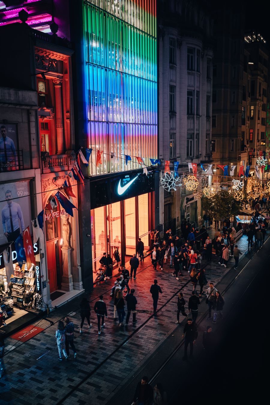 Gece ışıklı dükkânlar ve kalabalıkla dolu hareketli bir cadde