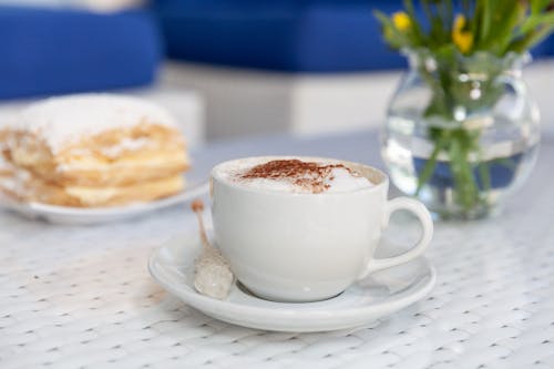 무료 접시에 커피 거품 가득한 찻잔 스톡 사진