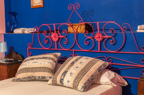 Red Steel Bed Frame Beside Blue Concrete Wall