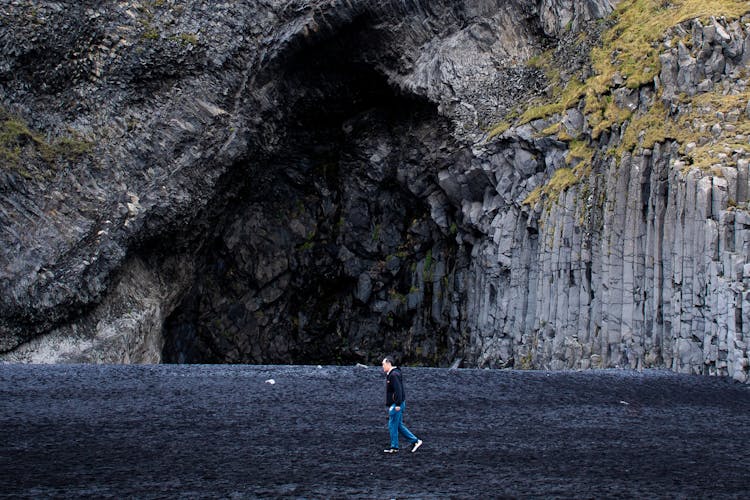 Man Walking On A Black Beach