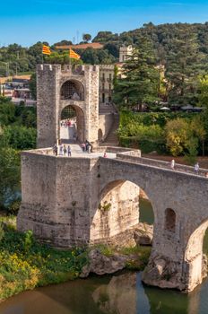 Aerial view of the iconic Medieval Bridge in Besalú, Spain, showcasing its historic architecture surrounded by nature.