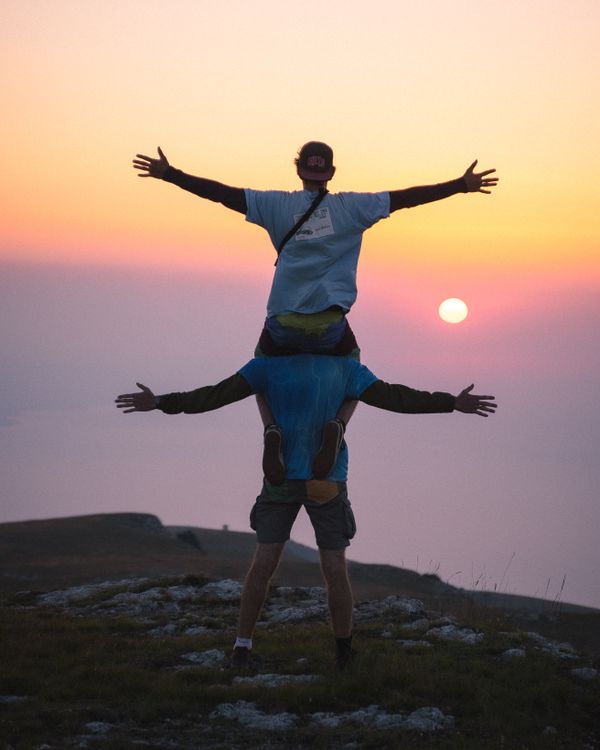 Serene men looking at the sun at sunrise with outstretched arms