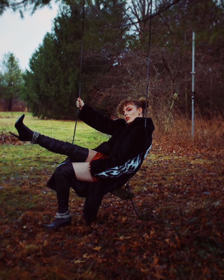 Woman Wearing Elegant Coat On Swing In Yard