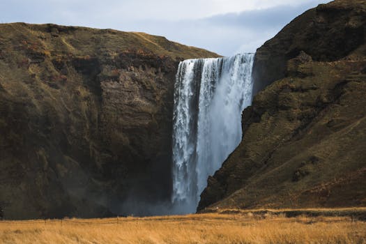 A breathtaking waterfall cascades down a rugged cliff in a rural landscape.