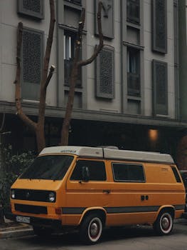 Classic yellow van parked against a modern building facade, creating a retro-urban contrast.
