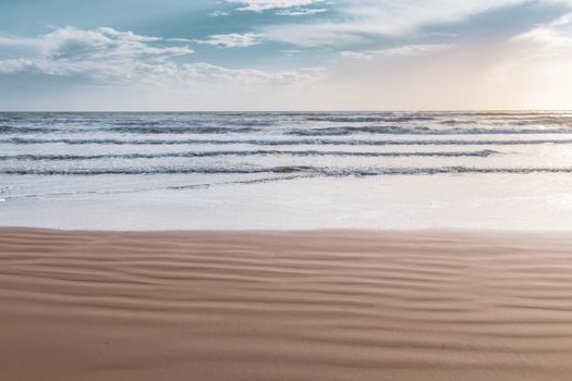 Calm beach scene at sunrise in Greece, capturing the gentle waves and sandy shore.