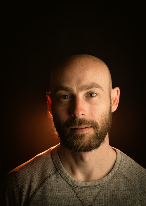 Free Close-up portrait of a bearded man with dramatic studio lighting against a dark background. Stock Photo