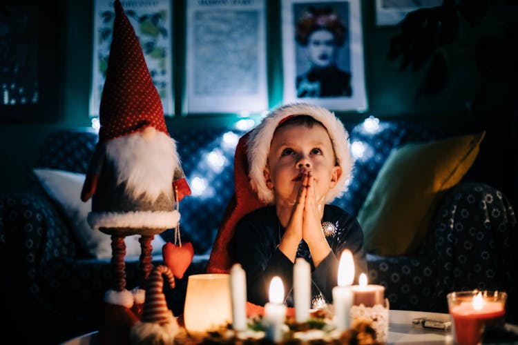 Toddler Praying In Front Of Candle Lights On Table