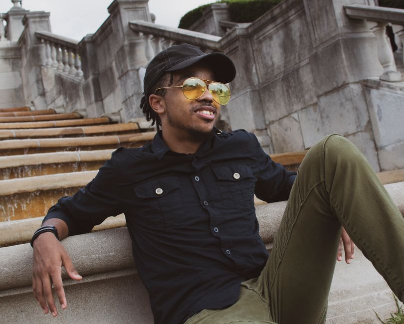 Stylish man in sunglasses relaxing on architectural stone steps.